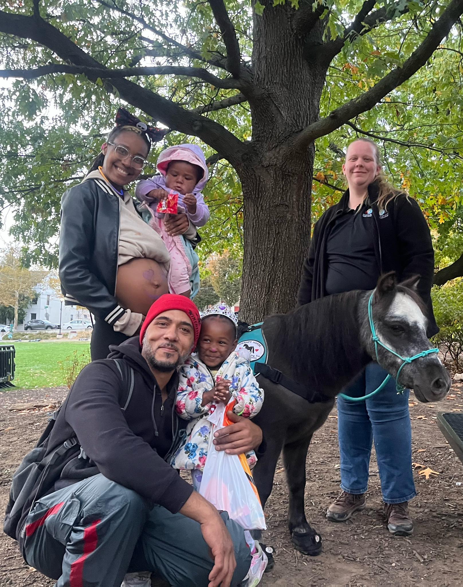 A family smiling with Sir Camelot at an outdoor community gathering