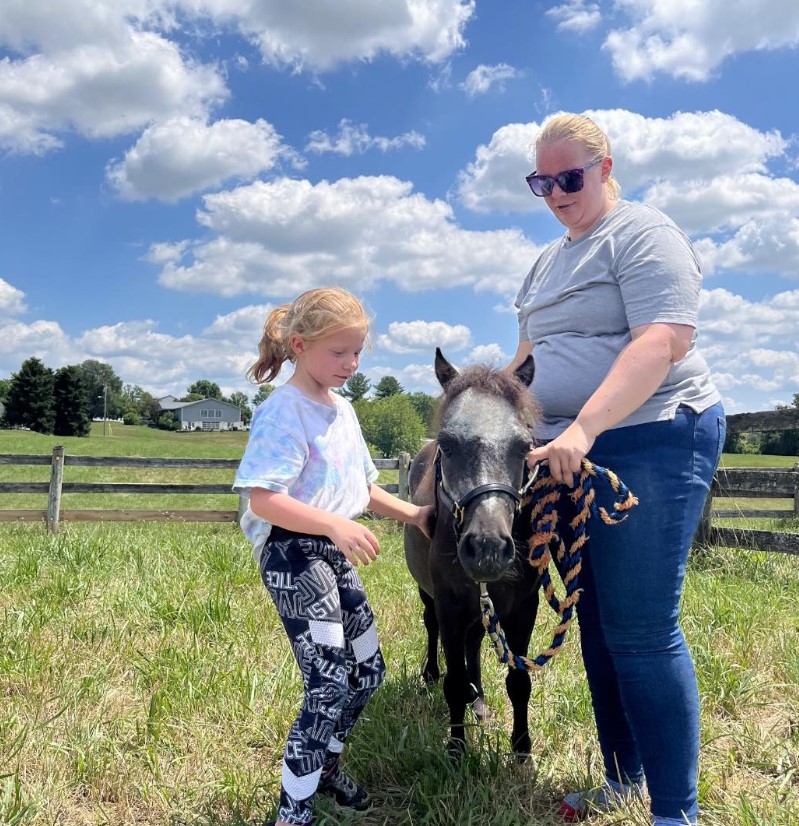 Kelsey Soult standing with a child and Sir Camelot